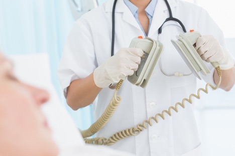 Doctor holding medical defibrillators by patient